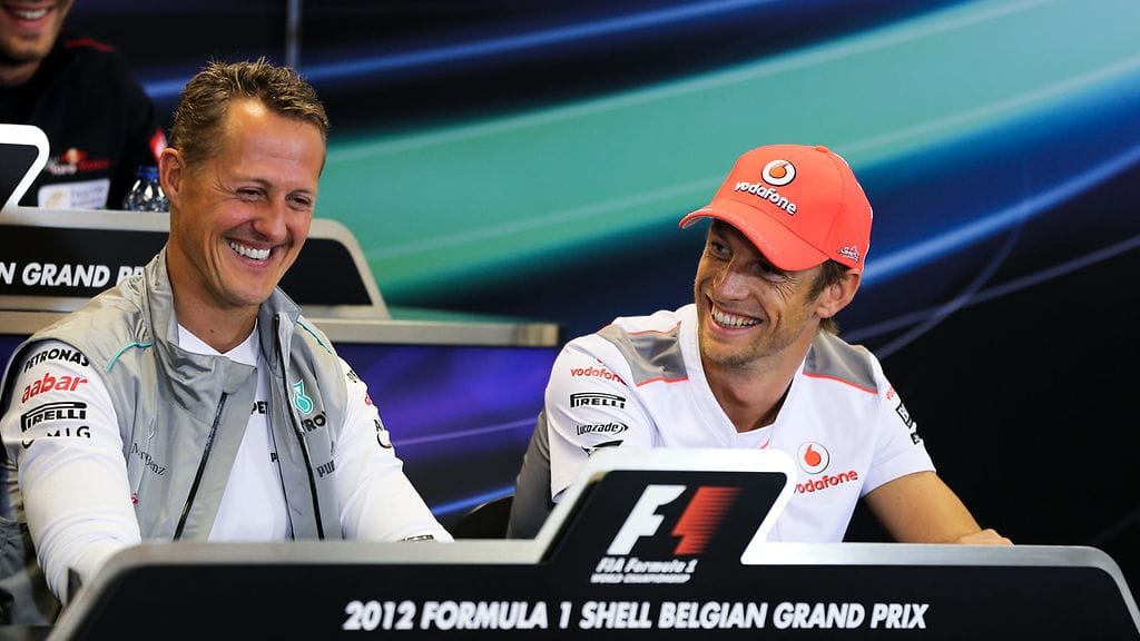 Jenson Button (oik.) ja Michael Schumacher hymyissä suin Belgian Span lehdistötilaisuudessa vuonna 2012.