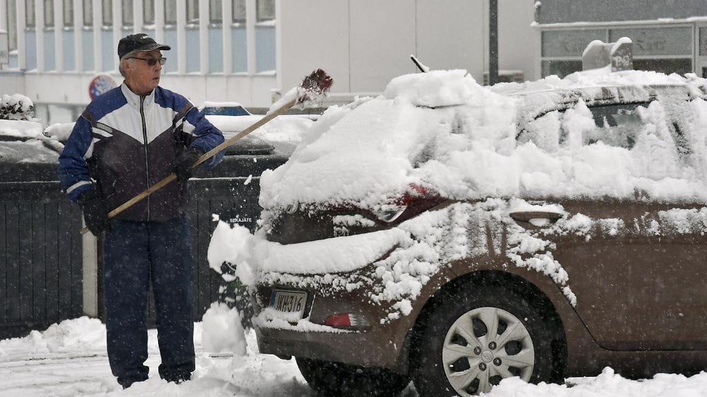 Mies puhdistaa autoa lumesta Tampereella torstaina 26. lokakuuta 2017.