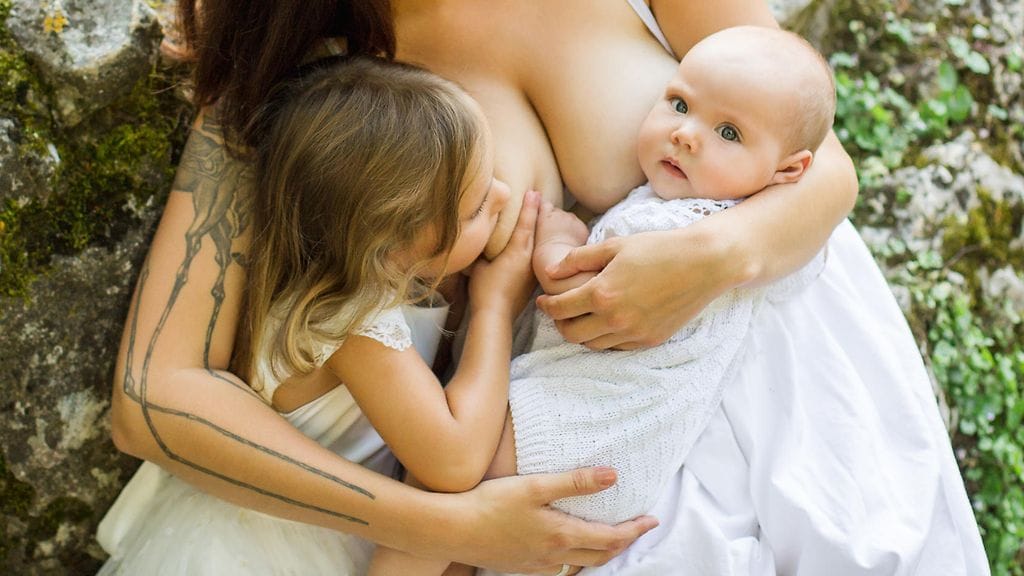 Äiti ruokkii 5- ja 2-vuotiaat lapsensa edelleen äidinmaidon avulla. Kuvituskuva.