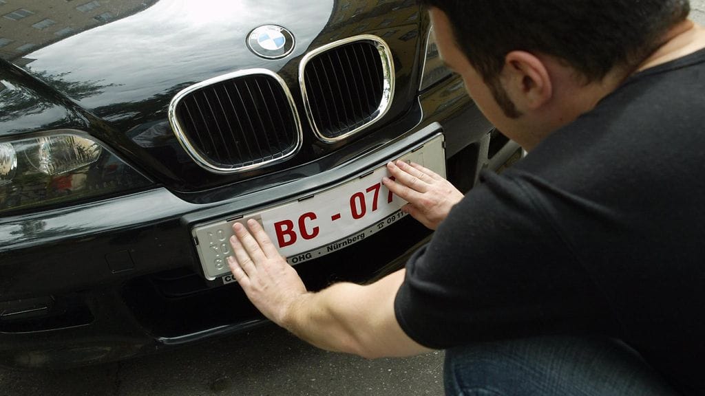 Saksasta tuotuun autoon kiinnitetään siirtokilpiä Helsingissä tiistaina 1. heinäkuuta 2003.