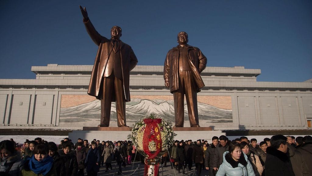 Ihmisiä Pohjois-Korean pääkaupungissa Pjongjangissa maan entisten johtajien Kim Il-Sungin ja Kim Jong-Ilin patsaiden alla 17. joulukuuta 2017.