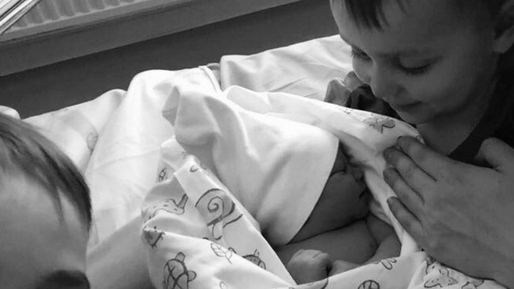 Outi ja Ville Kivistön lapset, uusin tulokas isompien sisarusten sylissä.