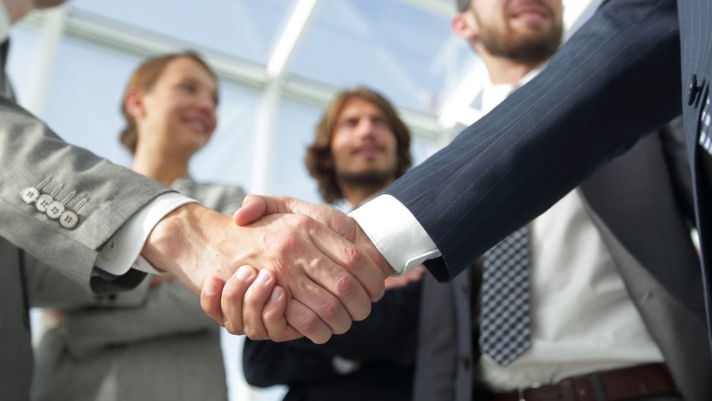 Reipas kädenpuristus hymyn kera antaa hyvän ensivaikutelman. Kuvituskuva.