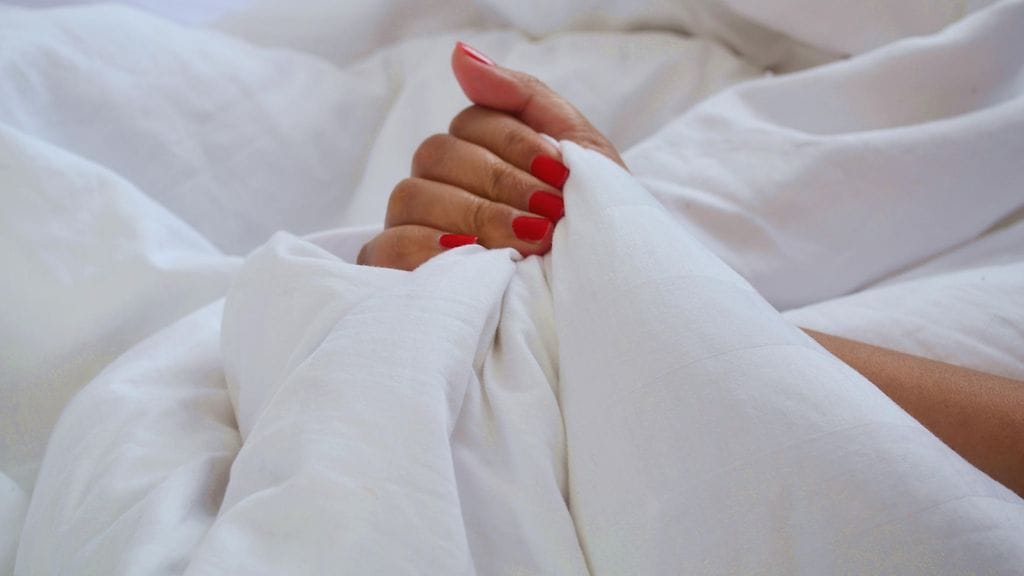naisen käsi sängyssä
