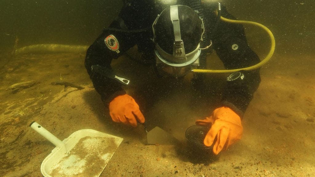 Eveliina Salo kaivaa vedenalaista liettä varovasti esiin.