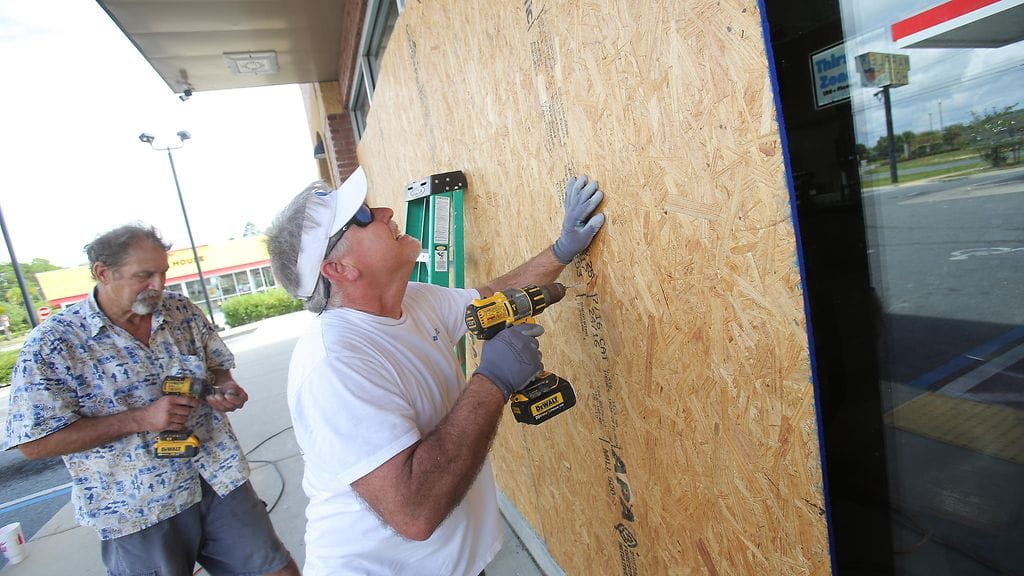 Floridassa varaudutaan hirmumyrskyn tuloon. Mikes Jones ja Dan Steele suojaavat huoltoaseman ikkunoita vanerilevyllä Panama Cityssa.