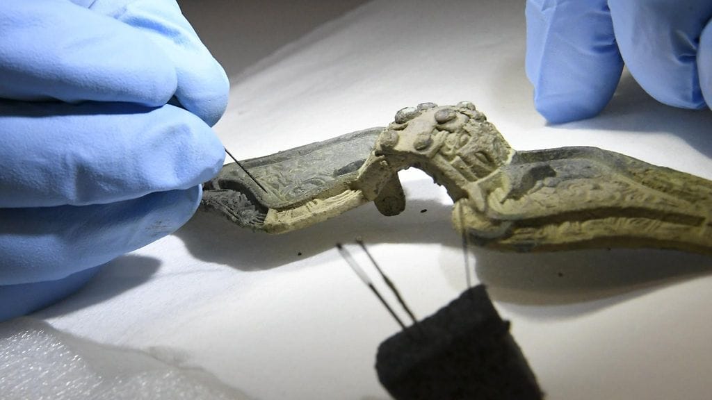 Konservaattori Pia Klaavu ja puhdistettavana oleva Sastamalasta löydetty, konsertoivana oleva solki Hakkilan konservointikeskuksessa Vantaalla 28. syyskuuta 2018.