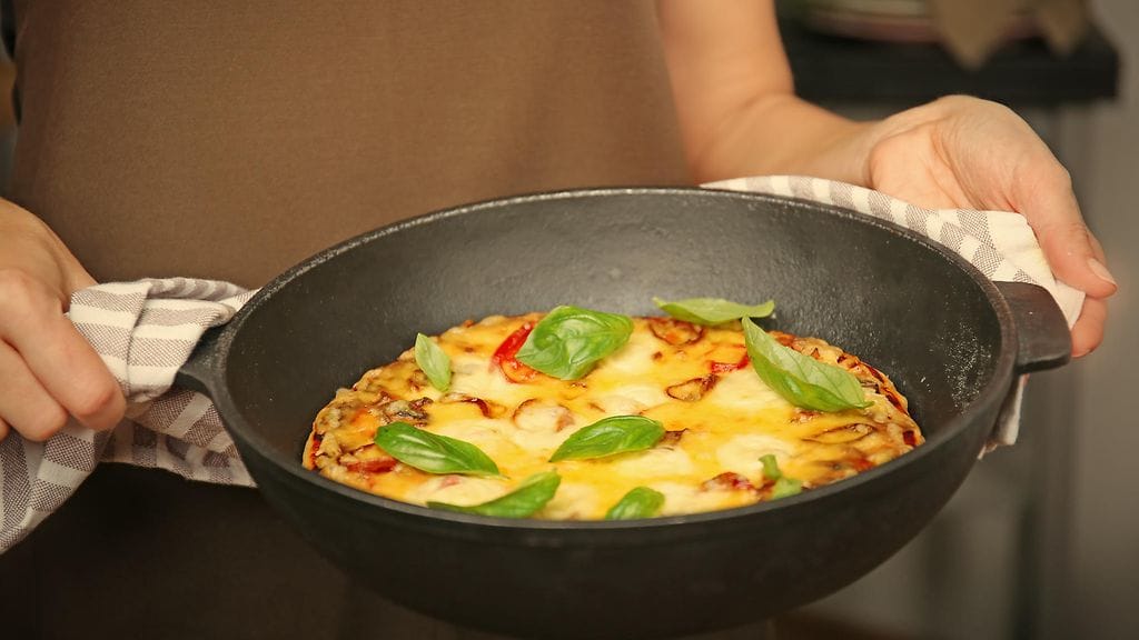 Pizzasta saa rapean, kun sen paistaa pannulla ja viimeistelee grillivastuksen alla uunissa.