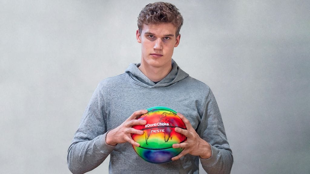 Lauri Markkasella on #DontChoke-kampanjan kuvissa käsissään koripallo, johon on maalattu maapallon lämpökartta viime kesältä.