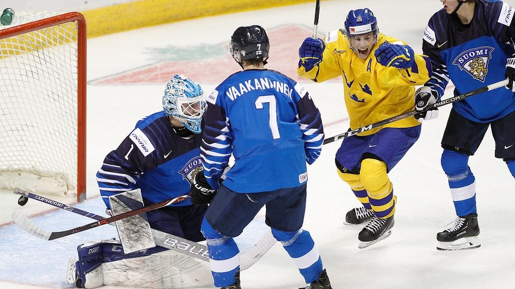 Ruotsin Rickard Hugg tuulettaa maalia suomalaispelaajien keskellä nuorten MM-kisojen avausottelussa.