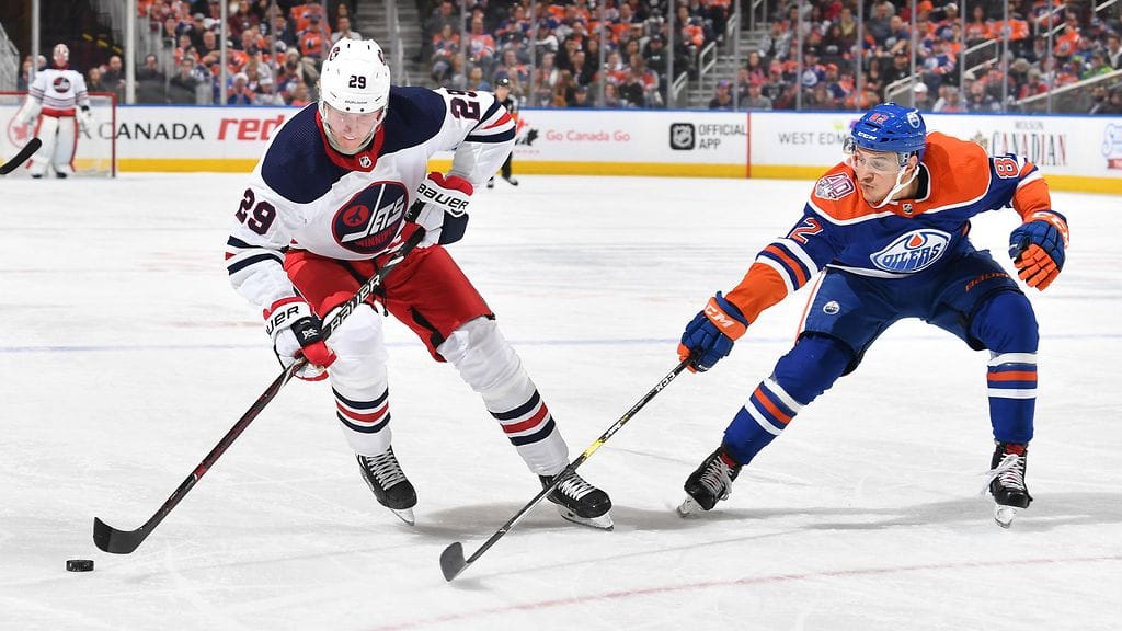 Patrik Laine suojaa kiekkoa Caleb Jonesia vastaan.