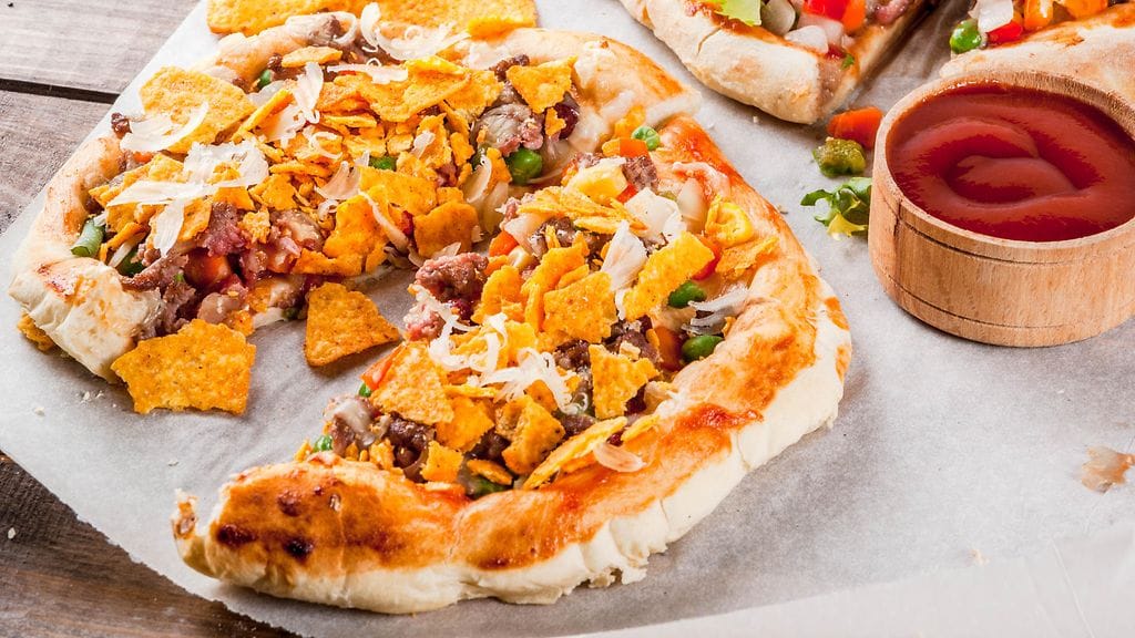 Taco-pizza tarjoillaan nachojen ja salsan kera.