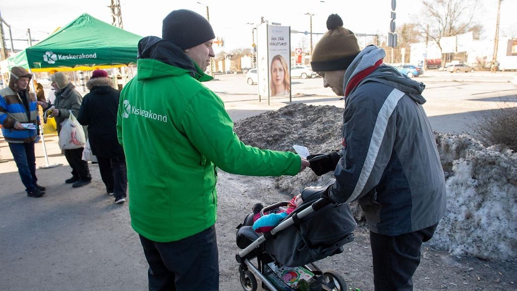 Mielipidekyselyissä ykkössija on vaihdellut nykyistä hallitusta johtavan keskustapuolueen ja opposition reformipuolueen välillä. Kuvassa pääministeri Jüri Ratas ojentaa esitettä.