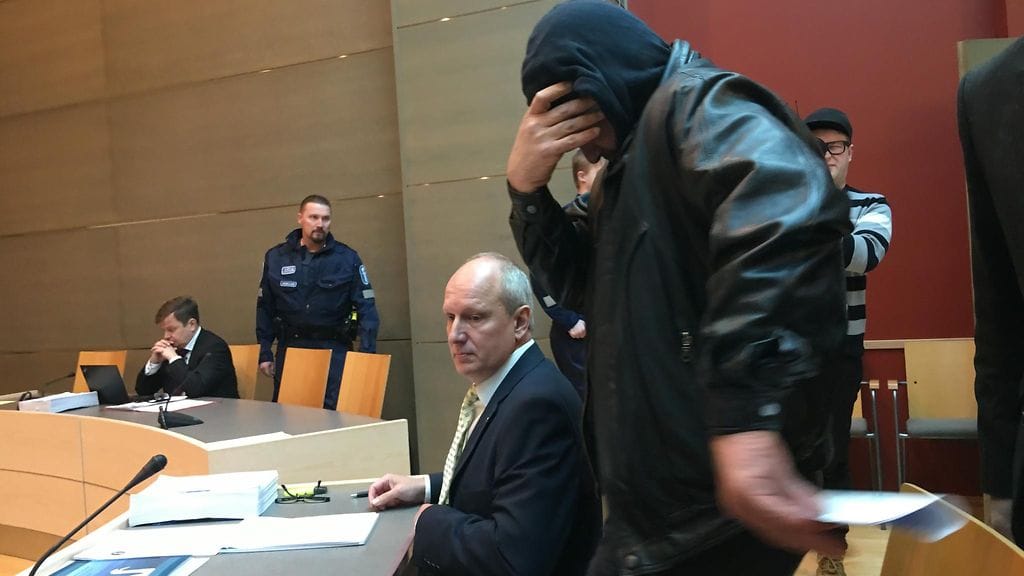 Henkirikoksesta syytetty irakilaismies saapui Kymenlaakson käräjäoikeuden istuntoon kasvojaan kameroilta peitellen.