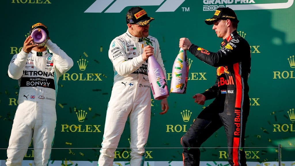 Valtteri Bottas (keskellä) sai voittajana kilistellä kuohujuomaa Australian GP:n jälkeen Red Bullin Max Verstappenin (oikealla) kanssa.