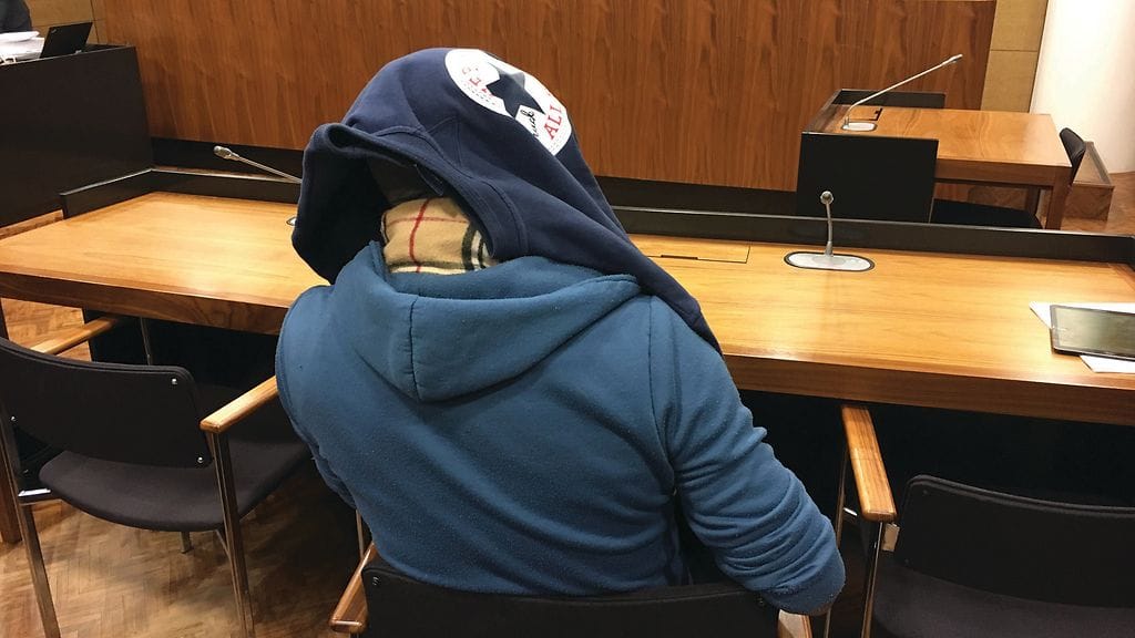 Murhasta syytetty isä peitti päänsä oikeudessa.