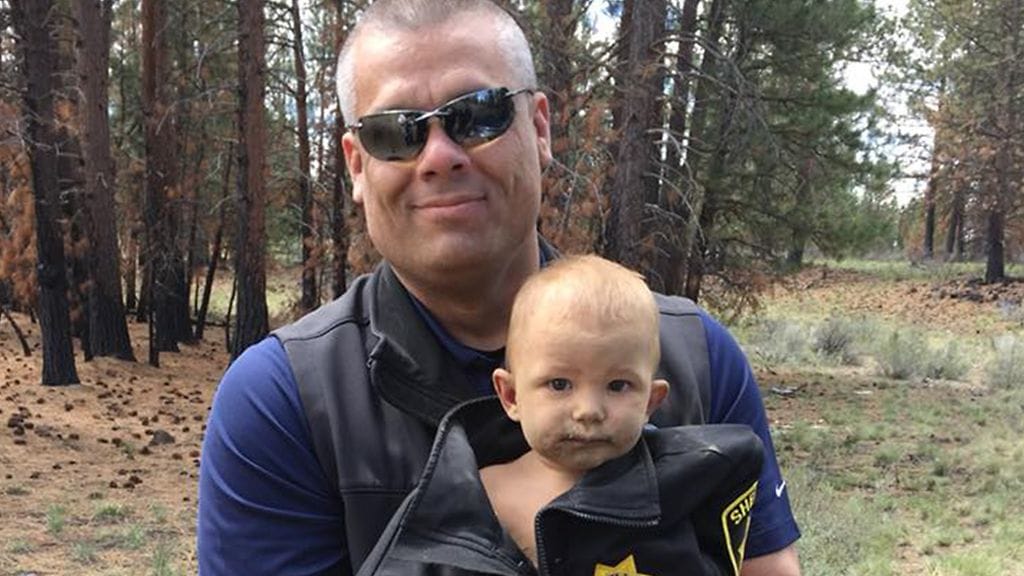 1-vuotias löydettiin metsästä hänen oltuaan kadoksissa noin vuorokauden. Tässä poika on kuvassa poliisin kanssa.