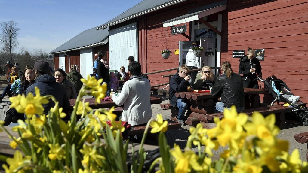 Ulkoilijat nauttivat terassilla aurinkoisesta kevät säästä Fallkullan kotieläintilalla Helsingissä pääsiäissunnuntaina 21. huhtikuuta 2019.