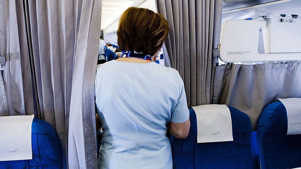 Finnairin lentoemäntä työskentelee lentokoneen matkustamossa lennon aikana.