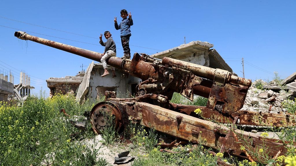 Syyrialaislapset istuivat vaurioituneen tykin päällä Kobanissa Syyrian pohjoisosassa huhtikuussa 2019.