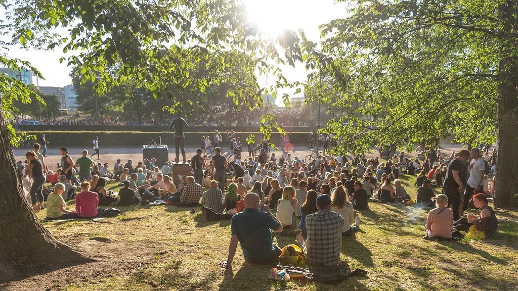 Ihmisiä viettämässä kesäpäivää Helsingin Kaisaniemen puistossa. Kuvituskuva.