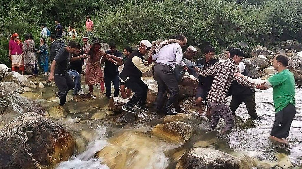 Paikalliset auttoivat bussin putoamisesta selvinneitä ylittämään joen.