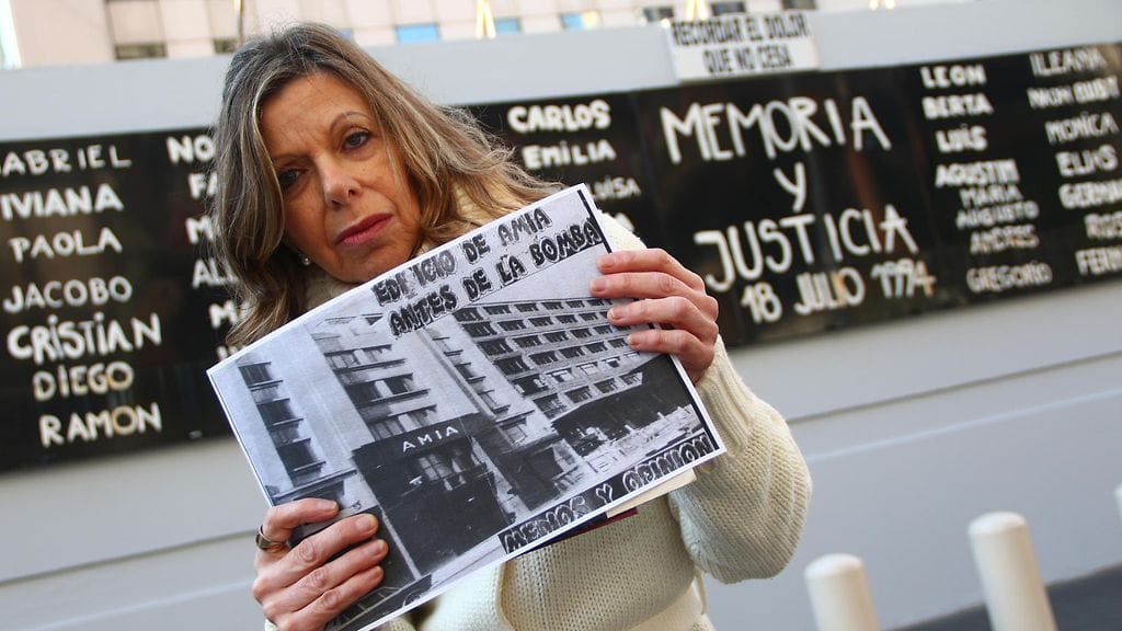 Pommi-iskusta selviytynyt Mirta Regina Satz seisoi uudelleenrakennetun kulttuurikeskuksen edessä vaatien oikeutta iskusta selvinneille ja heidän läheisilleen.