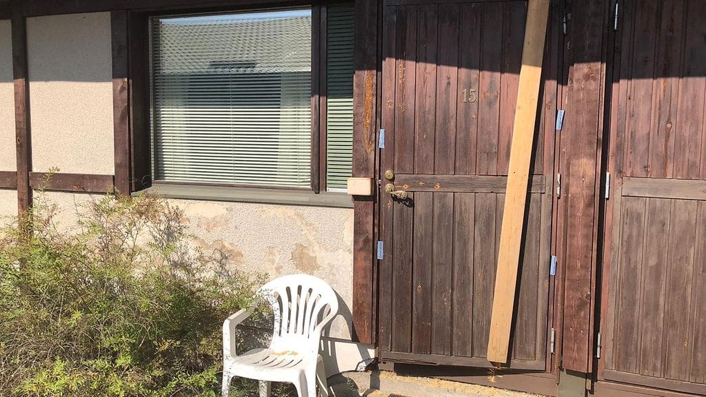 Poliisin hajottama motellihuoneen ovi on parsittu kasaan laudanpätkällä.