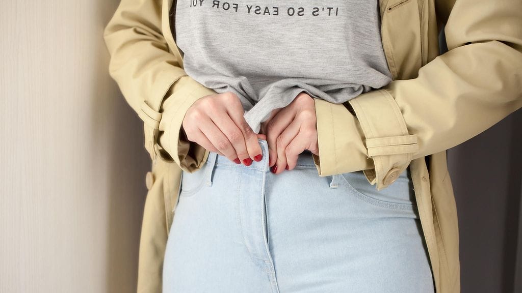 Pikkupoika kannusti farkkuja sovittanutta äitiään. Kuvituskuva.