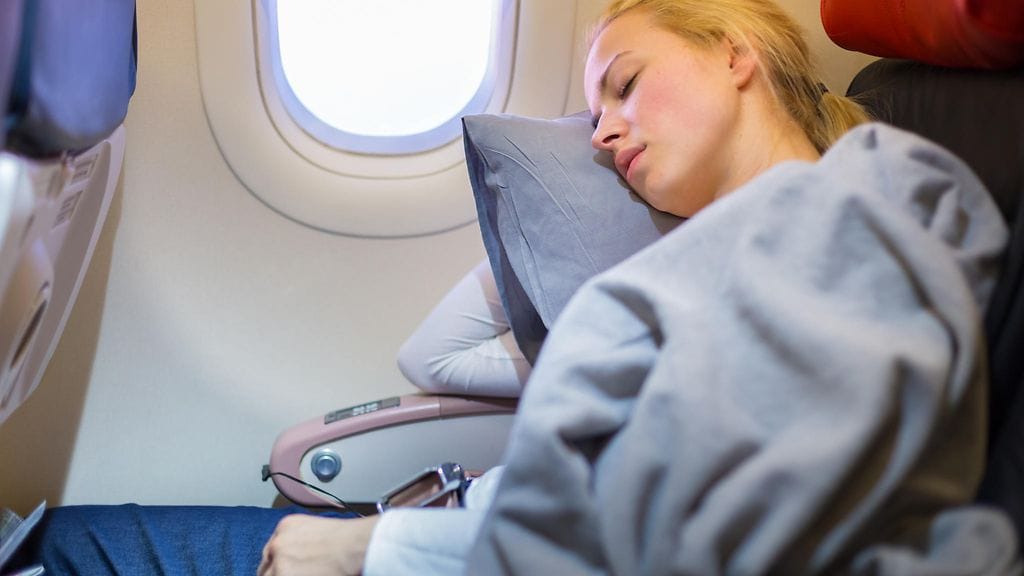 Monille unen saaminen pystyasennossa on vaikeaa. Kuvituskuvassa nuori nainen nukkuu lentokoneessa pää tyynyllä.