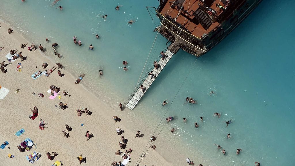 Ihmiset nousevat turistiveneeseen Zakynthosin saaren rannalla. Kuvituskuva.