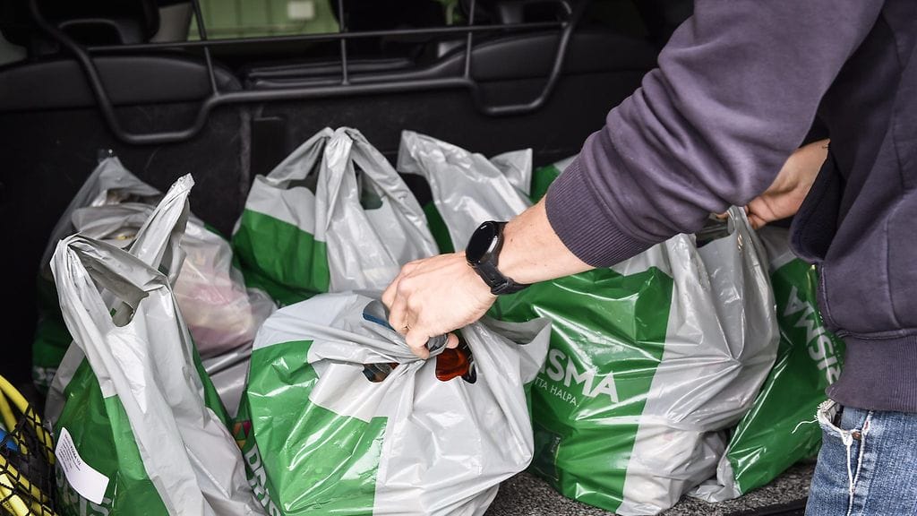 Isä purkaa lapsiperheen muovikasseissa olevia ruokaostoksia autosta kotipaihallaan Järvenpäässä heinäkuussa 2018.