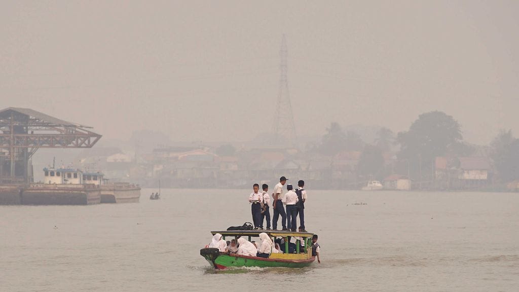Koululaiset matkaavat sankan savun läpi kouluun Indonesiassa.