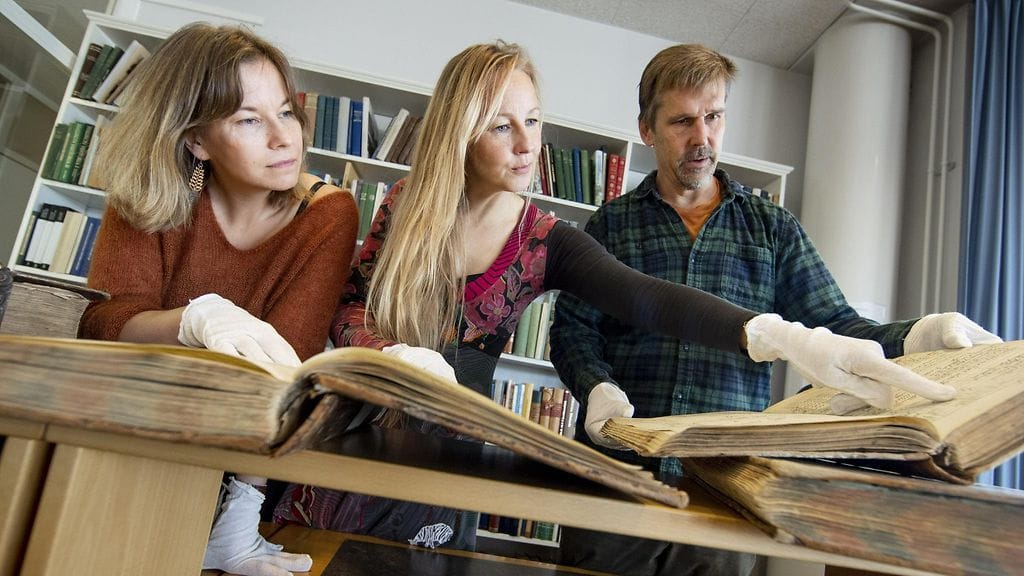 Turun yliopiston akatemianprofessori Virpi Lummaa (kesk.) sekä tutkijaryhmään kuuluvat Jenny Pettay (vas.) ja Robert Lynch Karjala-tietokantaan kuuluva kirkonkirjojen kanssa Turussa 17. syyskuuta 2019.