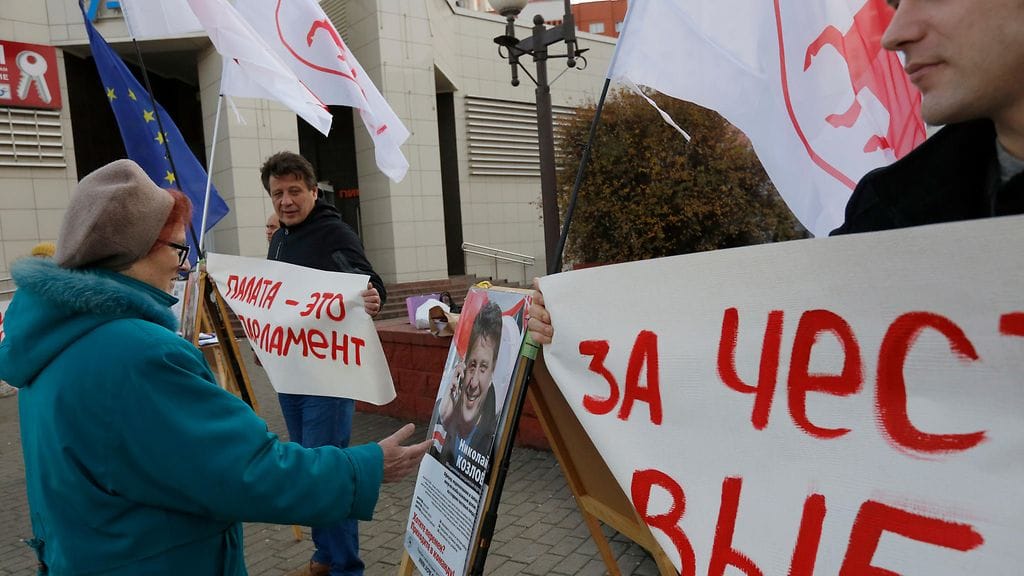 Nainen jutteli oppositioon kuuluvan Valko-Venäjän yhdistyneen kansanpuolueen aktivistien kanssa heidän osoittaessaan mieltään demokraattisten vaalien puolesta Minskissä viime keskiviikkona.