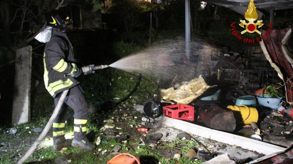 Viranomainen sammuttamassa räjähdyksessä syntynyttä paloa.