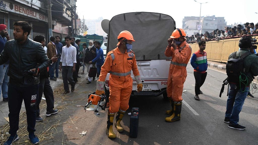 Pelastustyöntekijät pukivat varusteita ylleen tehdaspalon sammutustöitä varten Delhissä Anaj Mandin alueella.
