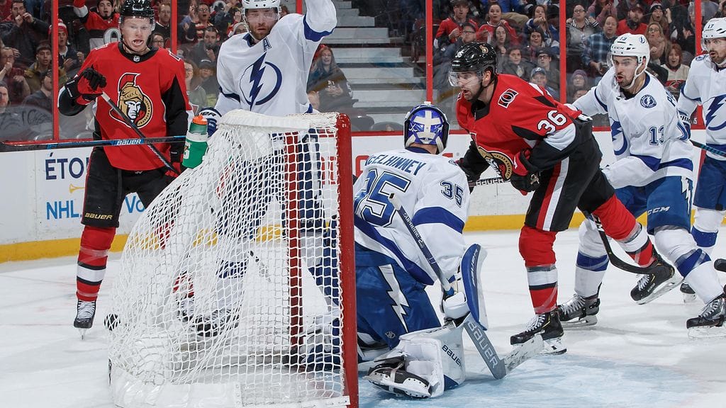 Colin White puski kiekon Curtis McElhinneyn maaliin.