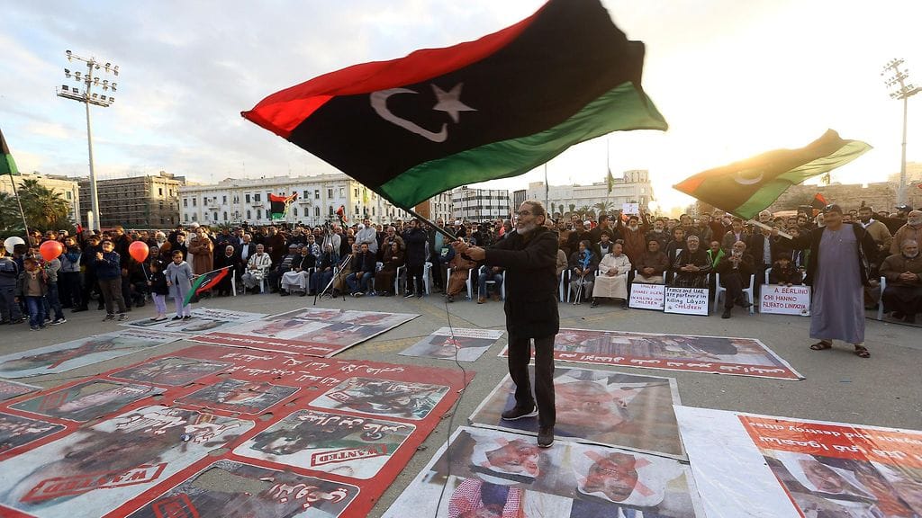 Mies heiluttaa Libyan lippua mielenosoituksessa.