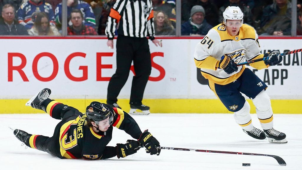 Quinn Hughes (vas.) taisteli kiekosta Mikael Granlundia vastaan.