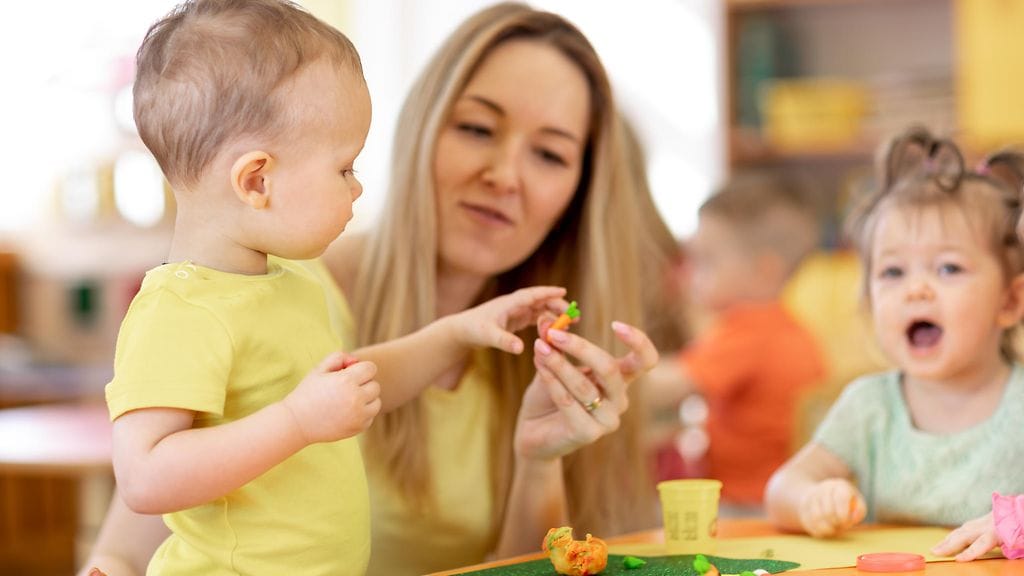 Nainen ja lapsia päivähoidossa, leikkii