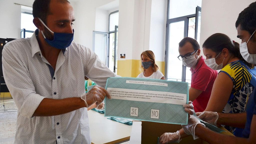 Italiassa koronaepidemia pakotti parlamentin kokoa koskevan kansanäänestyksen siirtämisen maaliskuulta syyskuulle viime vuonna. Kuvassa vaalivirkailija ja äänestäjiä Campaniassa.