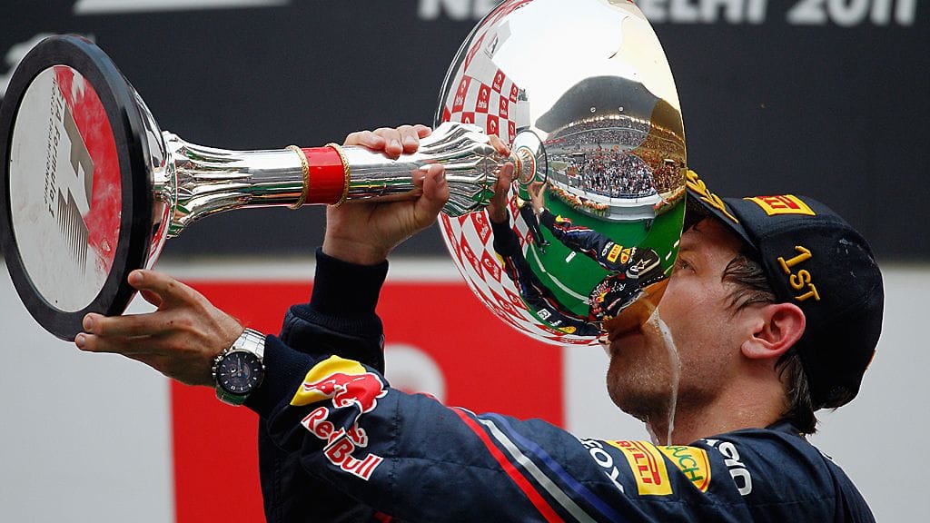 Sebastian Vettel nauttii samppanjaa Intian GP:n voittopokaalista