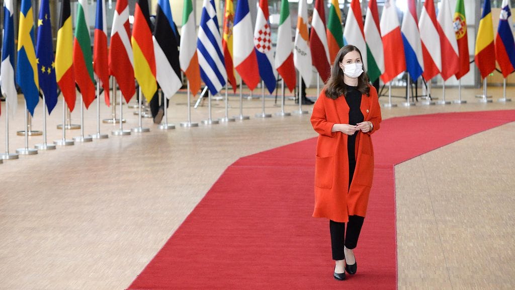 Sanna Marin EU-kokouksessa lippujen edessä.