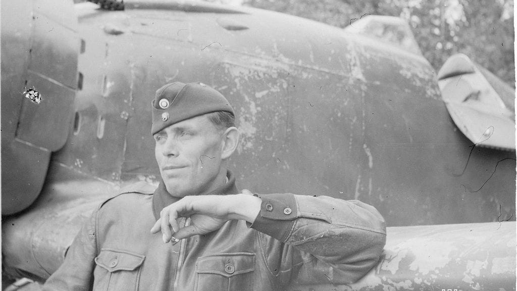 Vääpeli Oiva Tuominen nojaamassa lentokoneeseensa.