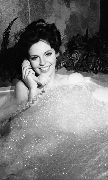 Nainen kylvyssä puhelimen kanssa