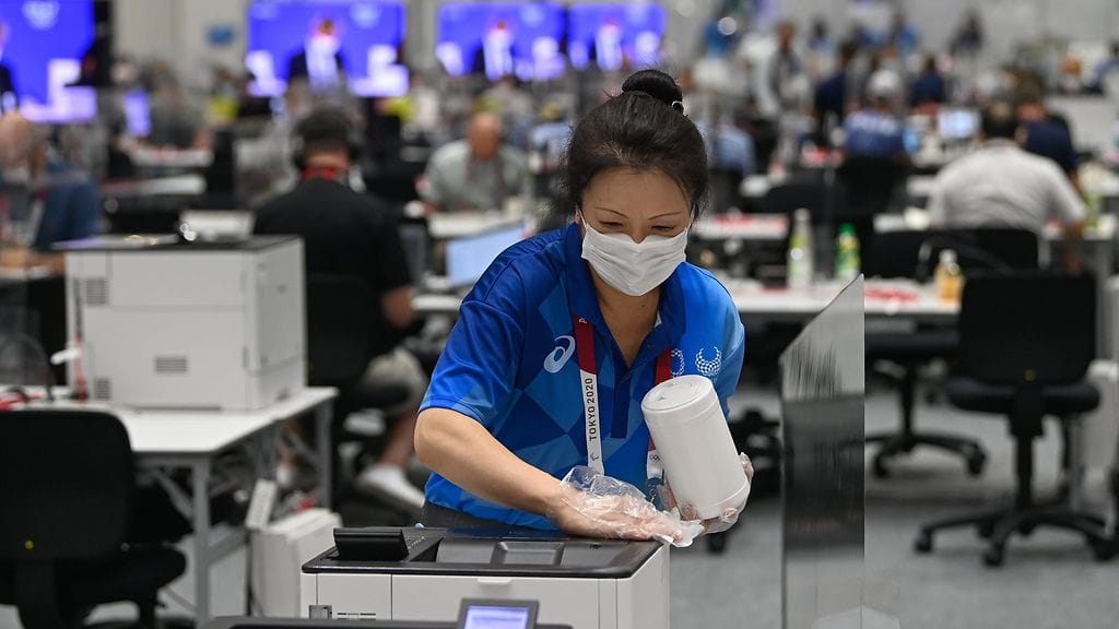 Siivooja desinfioi Tokion olympialaisten mediakeskuksen pintoja.