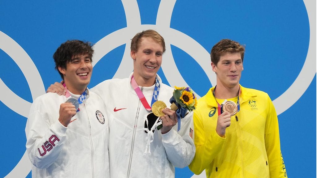 Hopeamitalisti Jay Litherland (vas.) olympiavoittaja Chase Kalisz ja pronssimitalisti Brendon Smith juhlivat sunnuntaina palkintokorokkeella ilman kasvomaskeja.