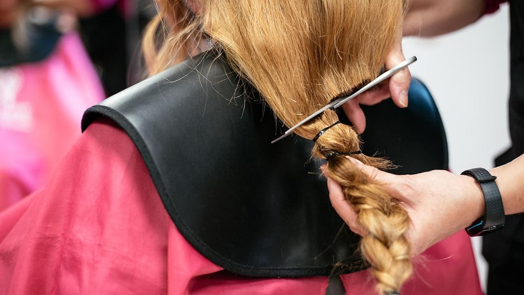 Kampaaja leikkaa pitkät hiukset