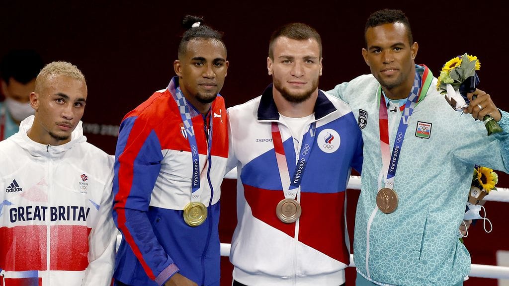 Olympiahopeamitalisti Benjamin Whittaker (vas.) pettyi jäätyään kakkoseksi ja laittoi palkintopallilla mitalinsa taskuunsa.